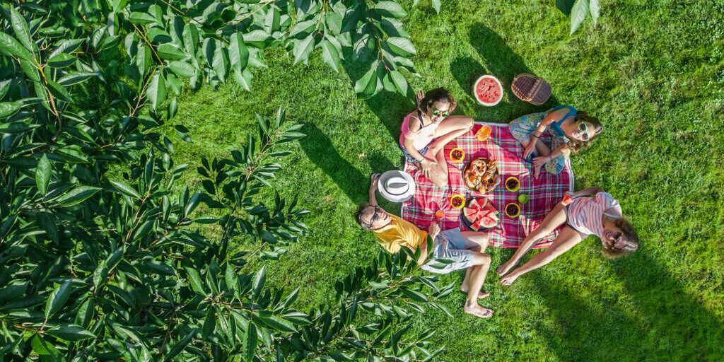 Happy family with children having picnic in park, parents with k